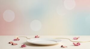 White plate sitting on top of a table next to pink flowers Background Image