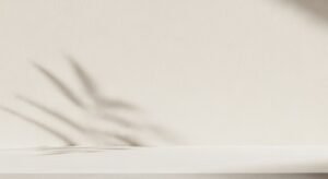 White shelf with a shadow of a plant on it Background Image